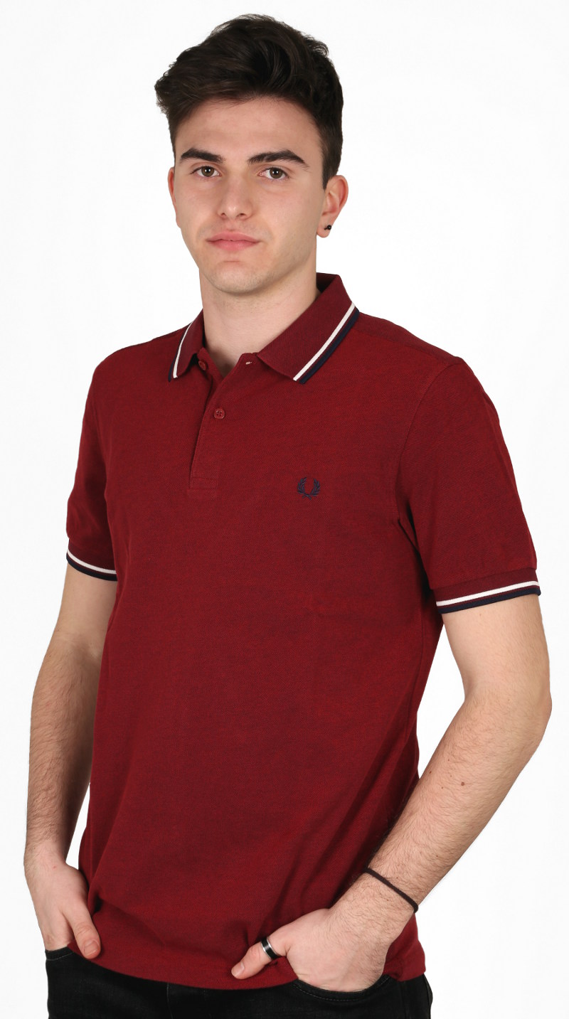 Polo 'classica' Fred Perry: manica corta, due bottoni, in piqué di cotone con tipping doppio 5-4-4 sul colletto e sui polsini; la variante di colore mostrata qui è la bramble blood oxford / white / navy